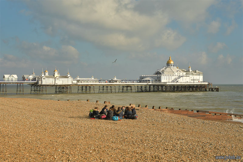 Group chilling out on the beach in front of Eastbourne’s Victorian pier